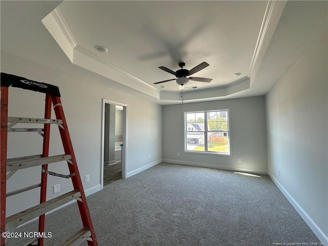 unfurnished bedroom featuring ornamental molding, carpet floors, a tray ceiling, and ceiling fan