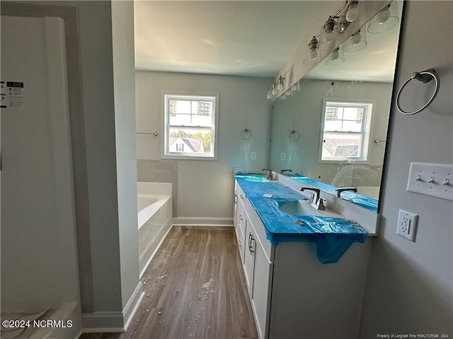 bathroom with vanity, a healthy amount of sunlight, hardwood / wood-style flooring, and a bath