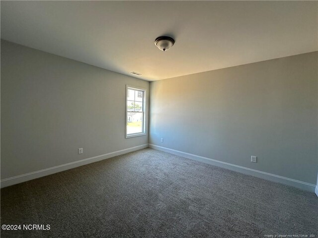 spare room with dark colored carpet