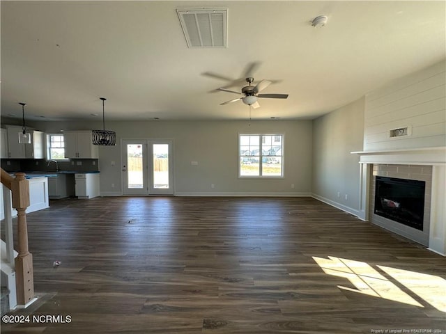 unfurnished living room with dark hardwood / wood-style floors, sink, a fireplace, and a wealth of natural light