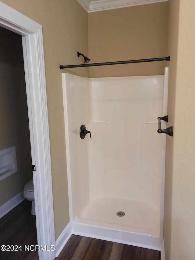 bathroom with hardwood / wood-style floors, a shower, crown molding, and toilet