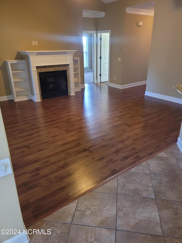 unfurnished living room featuring ornamental molding and dark wood-type flooring