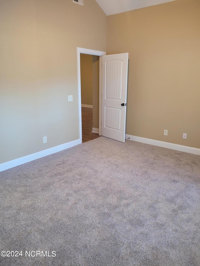 carpeted spare room with vaulted ceiling