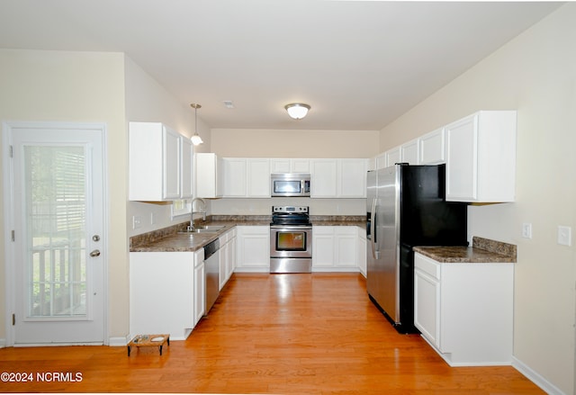 kitchen featuring white cabinets, light hardwood / wood-style flooring, stainless steel appliances, sink, and decorative light fixtures