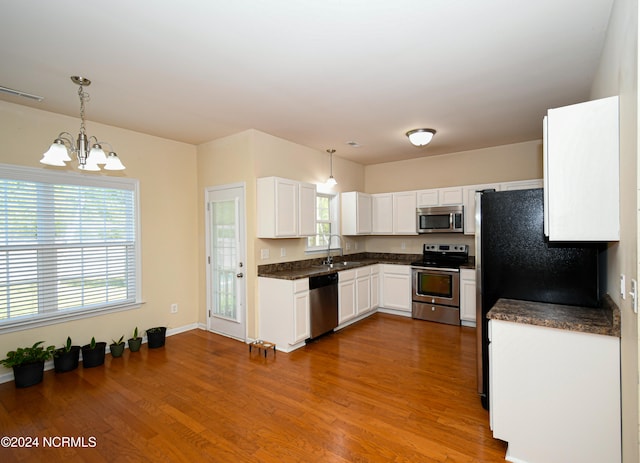 kitchen featuring a healthy amount of sunlight, hanging light fixtures, white cabinetry, light hardwood / wood-style flooring, and stainless steel appliances