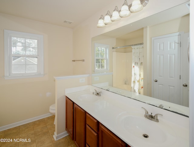 bathroom featuring vanity, tile patterned flooring, toilet, and walk in shower