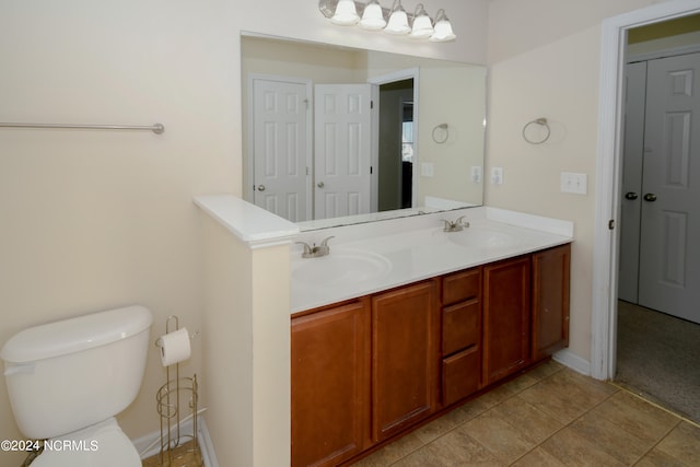 bathroom with toilet, vanity, and tile patterned flooring