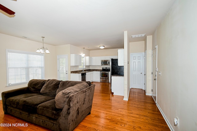 living room featuring sink, an inviting chandelier, and hardwood / wood-style floors