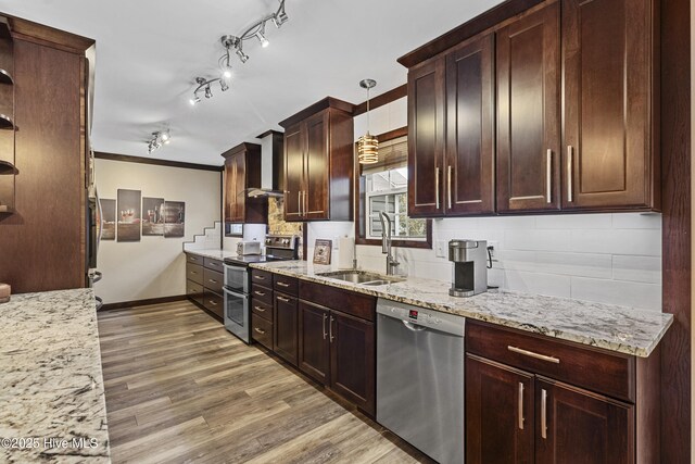 kitchen with tasteful backsplash, appliances with stainless steel finishes, sink, light wood-type flooring, and decorative light fixtures