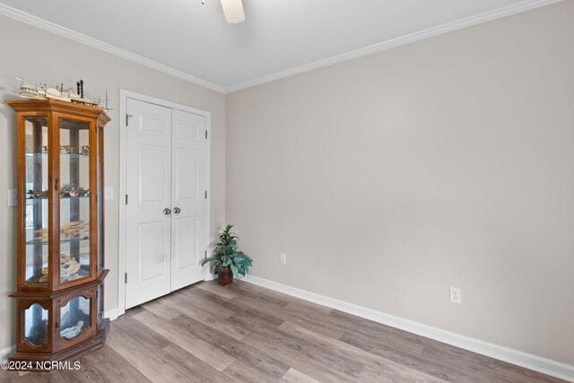 living area featuring a wall unit AC, light hardwood / wood-style flooring, crown molding, and vaulted ceiling