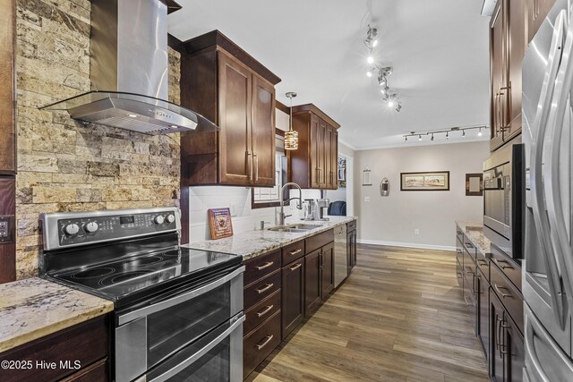 kitchen featuring appliances with stainless steel finishes, light wood-type flooring, a wealth of natural light, ornamental molding, and wall chimney exhaust hood