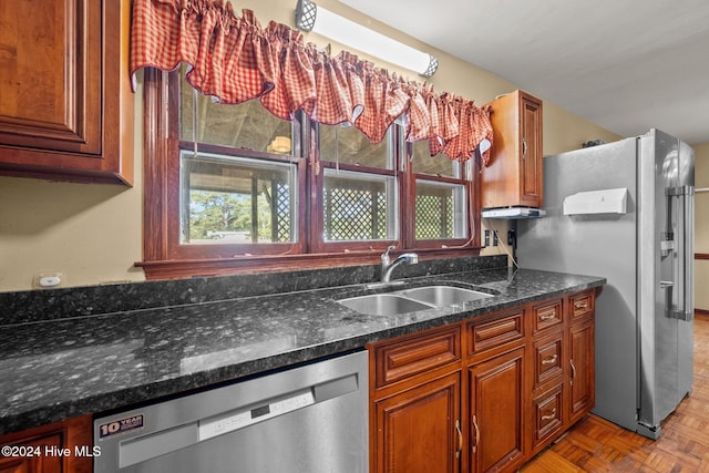 kitchen featuring dark stone counters, sink, parquet floors, and stainless steel appliances