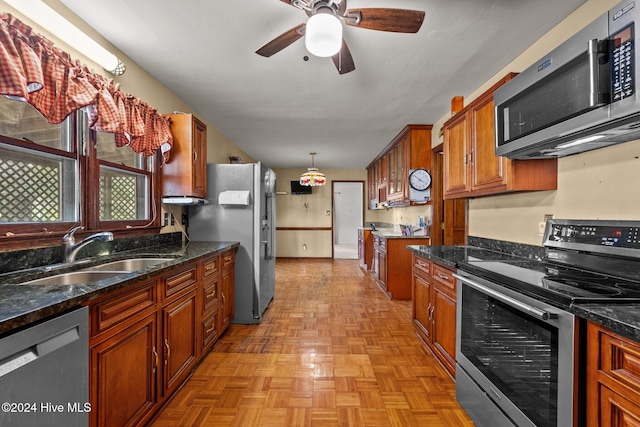 kitchen with light parquet floors, appliances with stainless steel finishes, decorative light fixtures, sink, and ceiling fan