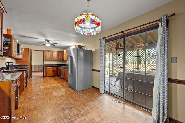 kitchen featuring light parquet floors, stainless steel appliances, pendant lighting, dark stone countertops, and ceiling fan