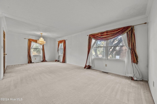 carpeted spare room with a healthy amount of sunlight, a textured ceiling, crown molding, and a notable chandelier