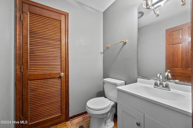 bathroom featuring toilet, vanity, and parquet flooring