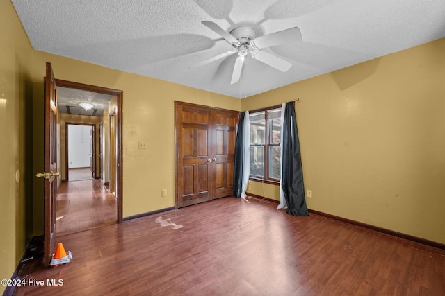 unfurnished bedroom featuring dark hardwood / wood-style flooring, a textured ceiling, and ceiling fan