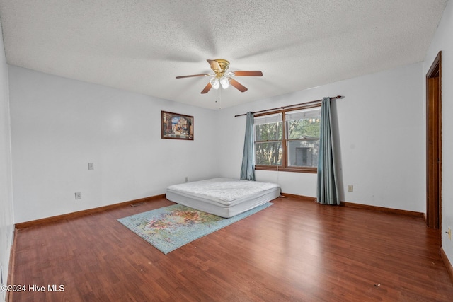 unfurnished bedroom featuring ceiling fan, a textured ceiling, and dark hardwood / wood-style floors