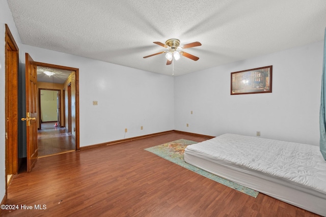 bedroom with hardwood / wood-style floors, a textured ceiling, and ceiling fan