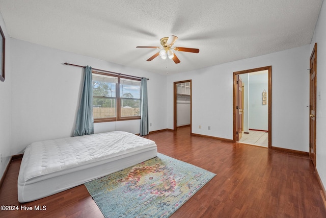 bedroom with ceiling fan, wood-type flooring, and a textured ceiling