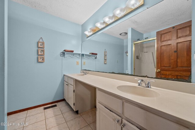 bathroom featuring vanity, tile patterned flooring, a textured ceiling, and a shower with door