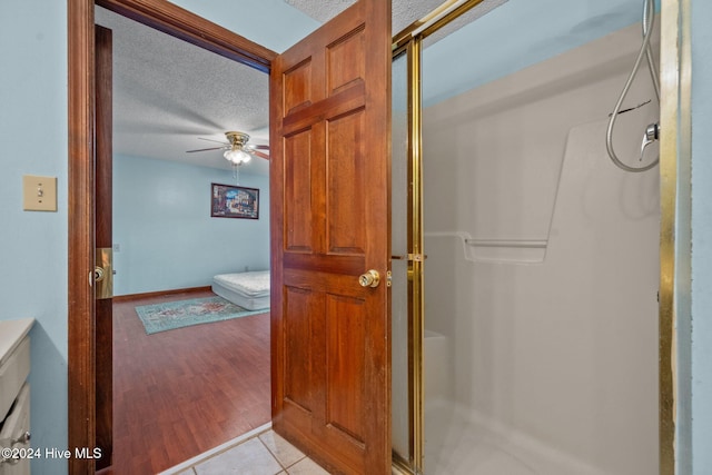 bathroom featuring walk in shower, hardwood / wood-style floors, ceiling fan, and a textured ceiling