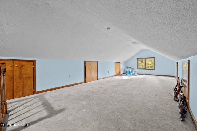 bonus room with light colored carpet, a textured ceiling, and vaulted ceiling