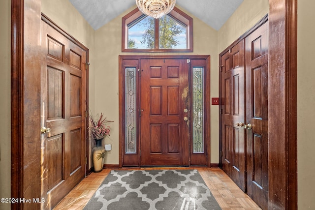 entrance foyer featuring light parquet floors, lofted ceiling, and a textured ceiling