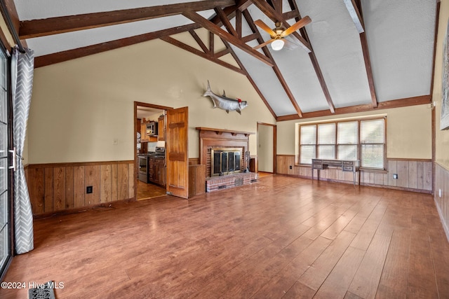 unfurnished living room with a fireplace, beam ceiling, high vaulted ceiling, ceiling fan, and light hardwood / wood-style flooring