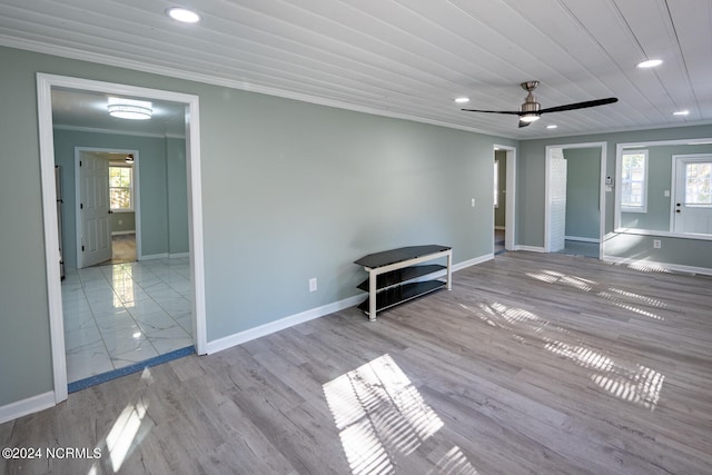 empty room with a healthy amount of sunlight, crown molding, light hardwood / wood-style floors, and ceiling fan