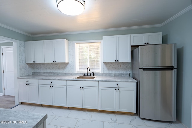 kitchen featuring sink, stainless steel fridge, white cabinets, and ornamental molding