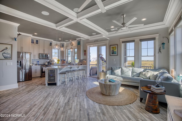 living room featuring light hardwood / wood-style flooring, ceiling fan, crown molding, and coffered ceiling