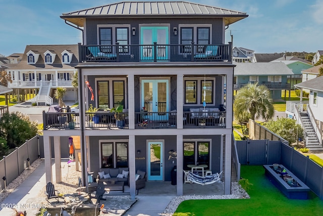 rear view of house with french doors, outdoor lounge area, a balcony, and a patio area