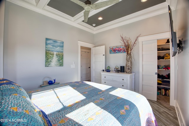 bedroom with a walk in closet, ornamental molding, a closet, wood-type flooring, and coffered ceiling