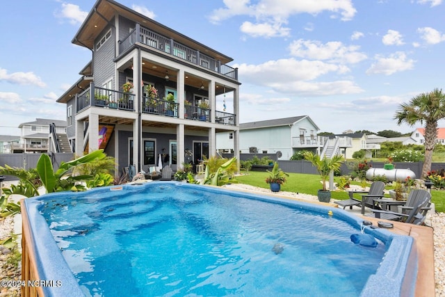 back of house with a fenced in pool and a balcony