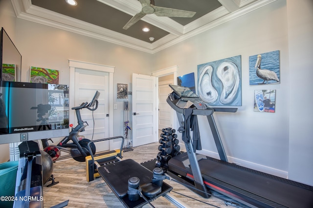 exercise area with ceiling fan, ornamental molding, light hardwood / wood-style floors, and coffered ceiling