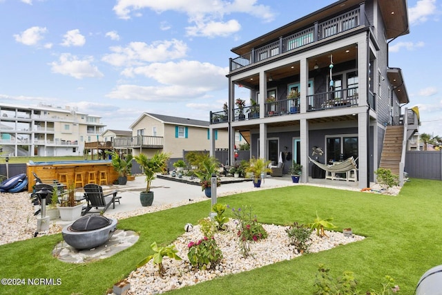 back of house featuring a patio, a yard, a fire pit, a balcony, and exterior bar