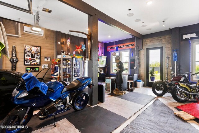 garage with wood walls, a wall unit AC, and stainless steel refrigerator