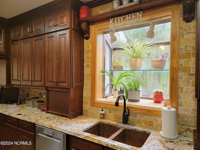 kitchen featuring light stone counters, sink, stainless steel dishwasher, and dark brown cabinetry