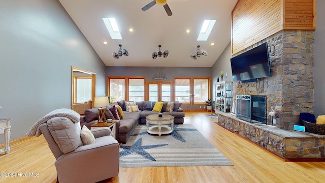 living room featuring a fireplace, a skylight, and high vaulted ceiling