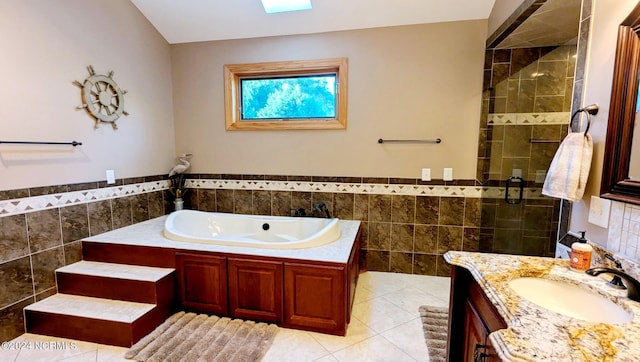 bathroom with tile patterned floors, plus walk in shower, tile walls, and vanity