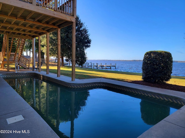 view of pool with a water view and a lawn