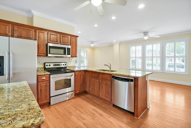 kitchen featuring crown molding, appliances with stainless steel finishes, light hardwood / wood-style flooring, and plenty of natural light