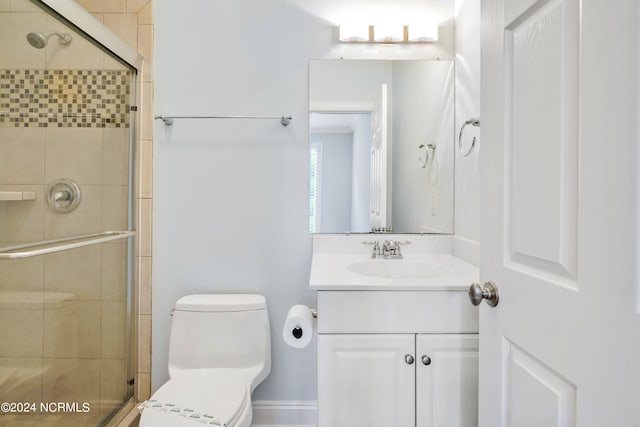 bathroom with vanity, toilet, and a shower with door