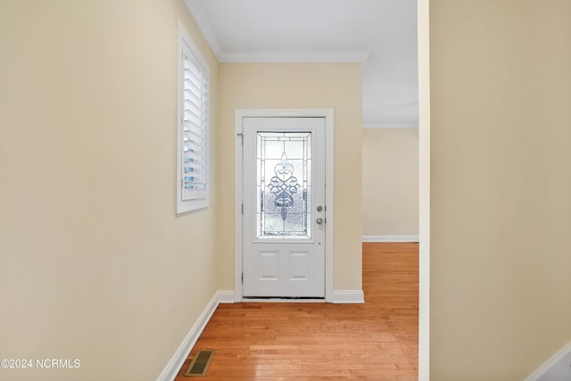 doorway with ornamental molding and light wood-type flooring