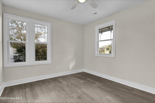 spare room featuring dark hardwood / wood-style floors, ceiling fan, and a wealth of natural light