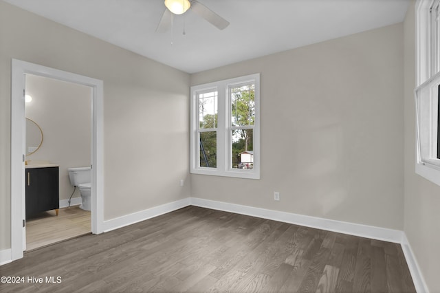 unfurnished bedroom with dark hardwood / wood-style flooring, connected bathroom, and ceiling fan