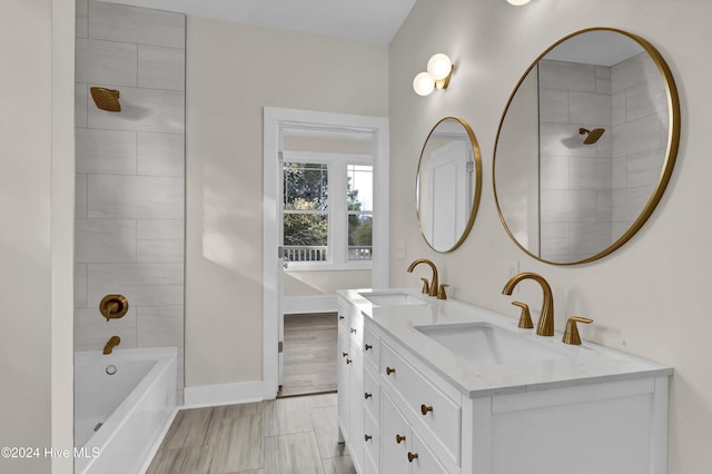 bathroom with hardwood / wood-style flooring, vanity, and tiled shower / bath