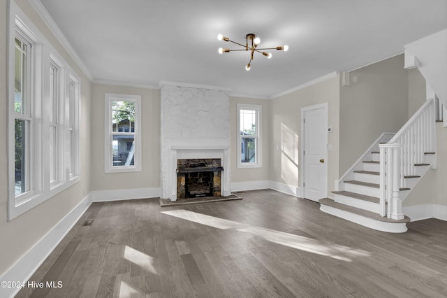 unfurnished living room with a fireplace, wood-type flooring, crown molding, and a notable chandelier