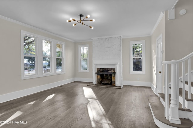 unfurnished living room with a notable chandelier, crown molding, wood-type flooring, and a fireplace